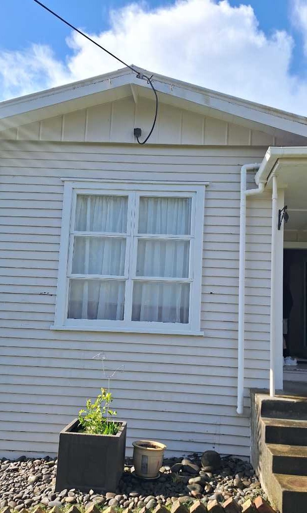 Exterior painting Auckland — crisp white weatherboard with freshly painted window joinery and downpipe